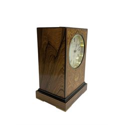 Knight & Gibbins London - 20th century 8-day marquetry inlaid mantle clock in rectangular case on a short plinth, glazed circular dial with Roman numerals and steel moon hands, two train striking movement with a floating balance escapement striking the hours and half hours on a bell, rear set and wound. With key.   