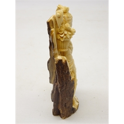  19th century Japanese carved Mammoth figure of a young woman collecting flowers, the reverse uncarved leaving a bark like texture, with signature to base, on hardwood stand, H13cm   