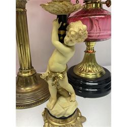 Victorian cast brass oil lamp, with fluted pink glass shade, together with two smaller brass oil lamps with pink shades and reservoirs and a pair of oil lamps, the bases modelled as putti, with pink glass reservoir  and frosted shades, tallest H70cm