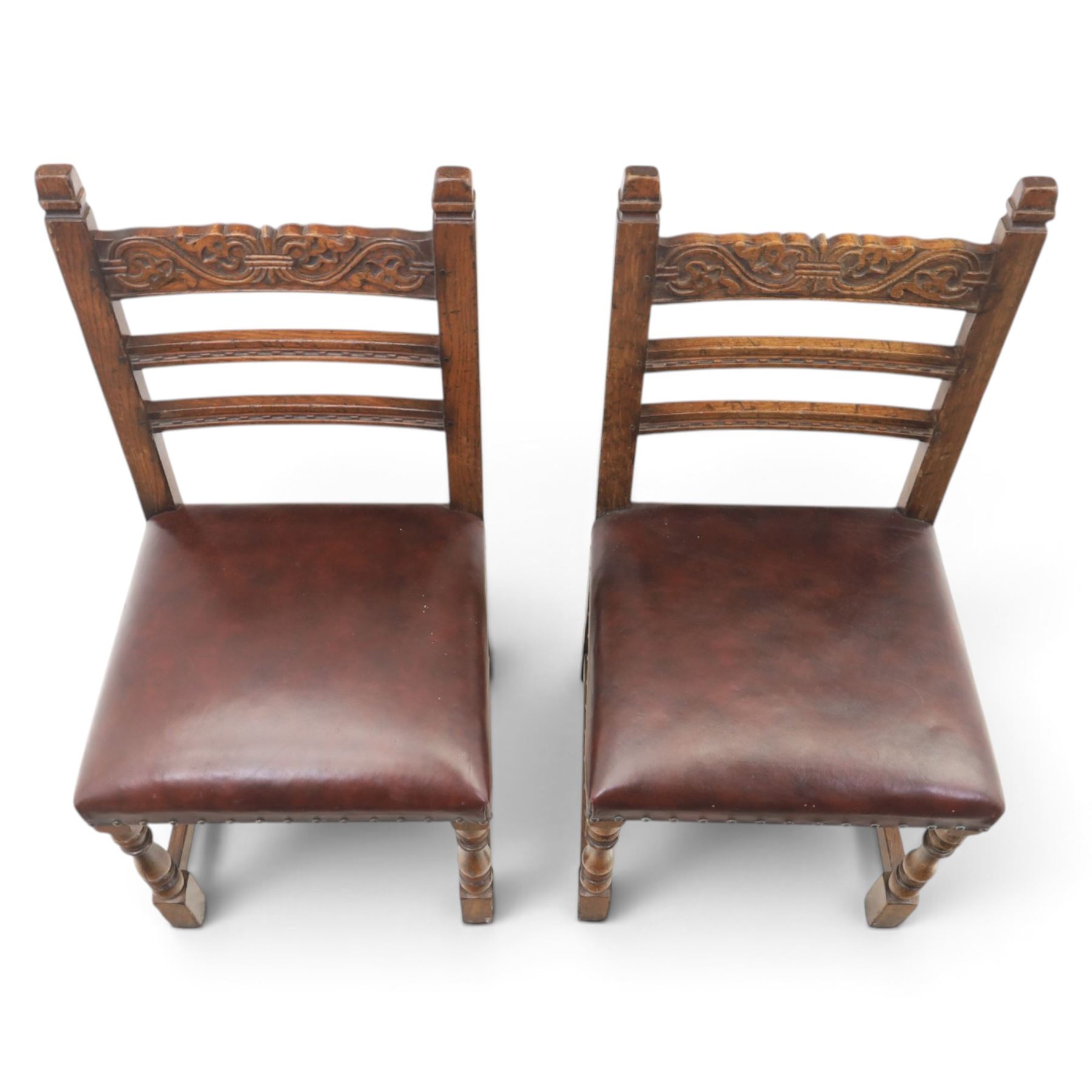 Craftsman made set of four solid oak dining chairs with leather seats, with carved cresting rail, on red leather seats with studded trim, raised on block and turn supports united by H-stretcher