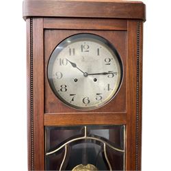 1930s striking wall clock with a spring driven  8-day movement sounding the hours on a gong, with a silvered dial, Arabic numerals and minute track, mahogany case with a glazed door and visible pendulum.