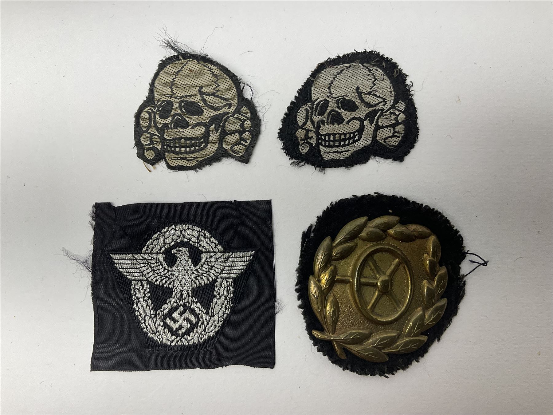 Collection of eleven German metal and cloth badges and uniform buttons including driver's badge, two 'SS' fabric skulls, private's shoulder tabs, Police cloth badge, tank destruction badge, medal bars and ribbon etc; most WW2 period