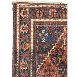 Persian Hamadan red ground rug, the field decorated with floral motifs with central lozenge medallion, guarded border decorated with repeating stylised plant motifs