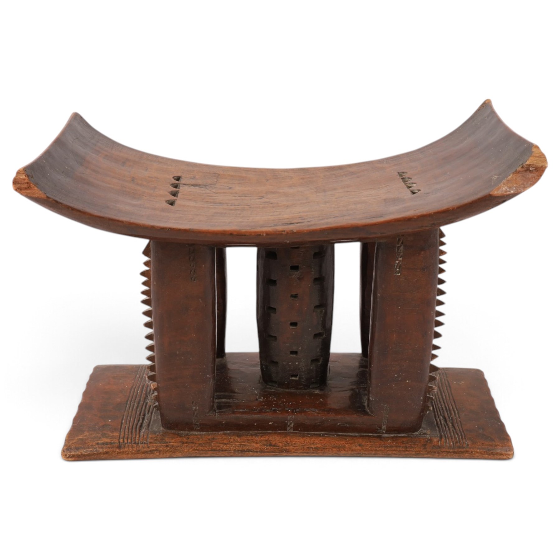 African carved hardwood headrest, having flared edges, raised on a stepped plinth base with further carved detailing, H34cm