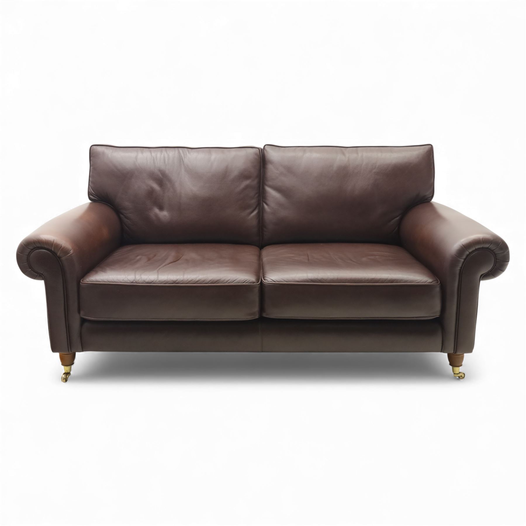 Laura Ashley - brown leather two seater sofa, loose cushion back and seat, flanked by scrolled arms upon light stained wood supports on castors