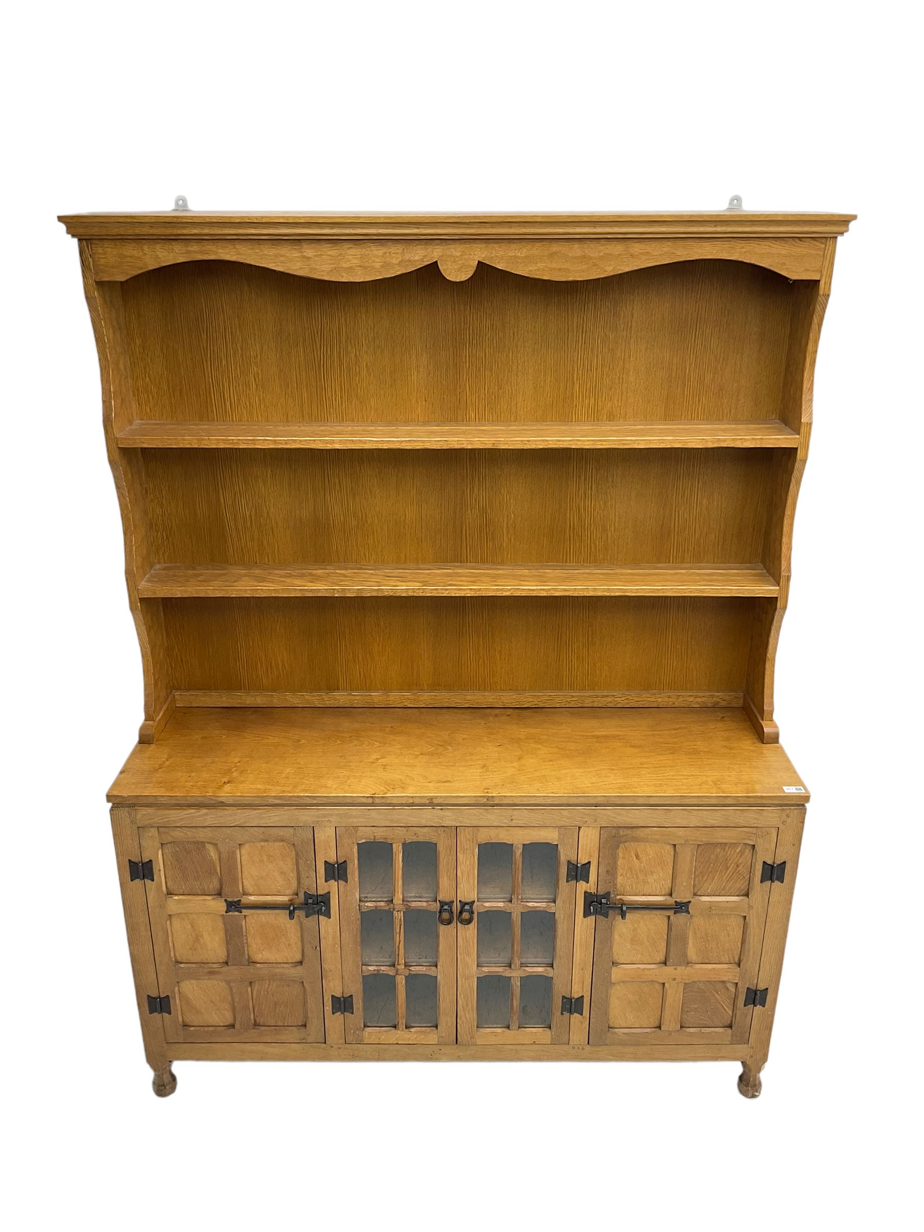 Yorkshire oak - adzed oak dresser, the rack with projecting cornice over shaped frieze and two shelves, the dresser fitted with central glazed double cupboard flanked by two panelled single cupboards, panelled sides