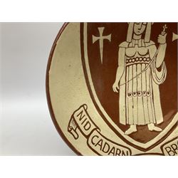20th century Dewi Bowen Welsh studio pottery plate, decorated with the Merthyr Tydfil coat of arms, depicting Saint Tydfil beneath a banner inscribed with the motto Nid Cadarn Ond Brodyrdde (No strength but in fellowship), signed and dated 1972 verso, D29cm.