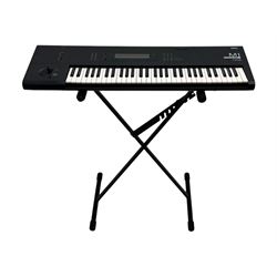 Korg M1 keyboard synthesiser, 61 velocity-sensitive keys with integrated multi-effects and eight-track sequencer, mounted on an adjustable black tubular X-frame stand with rubber end caps