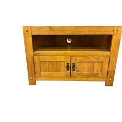 Solid light oak corner television stand, chamfered rectangular top over single shelf and two panelled cupboard doors