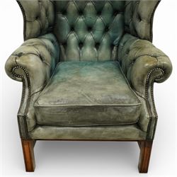 Georgian design mahogany framed wingback armchair, upholstered in rustic pale green buttoned leather with loose seat cushion, raised on square supports united by H-stretcher
