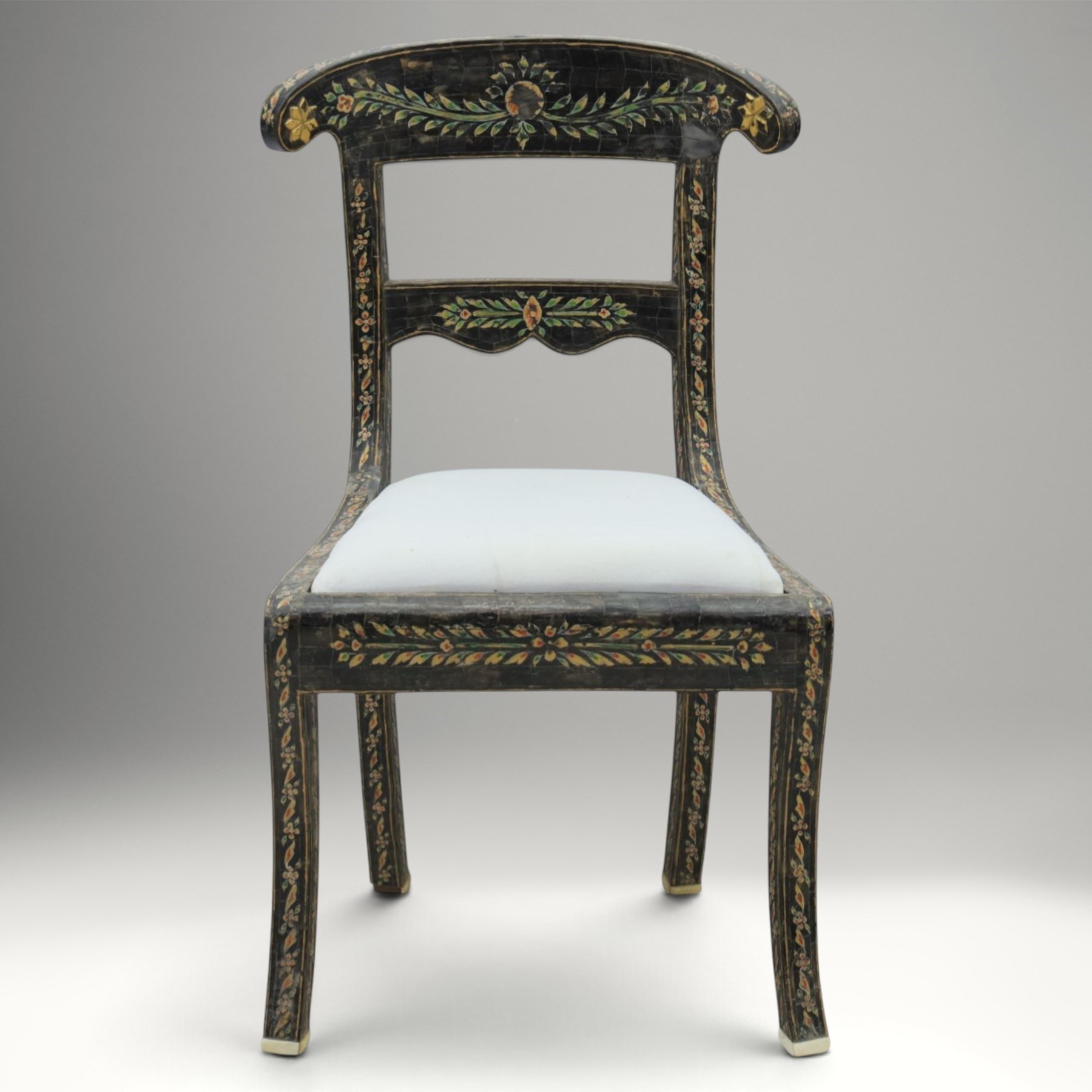 Early 20th century Anglo-Indian painted and inlaid armchairs, each with shaped top rail decorated with polychrome floral motifs above turned spindle galleries, shaped open arms and upholstered seats, on square supports with similar painted decoration
