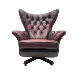 Mid-20th century Blofeld swivel and reclining armchair, triangular wingback over scrolled arms, upholstered in buttoned oxblood leather with studwork, on quadruform base