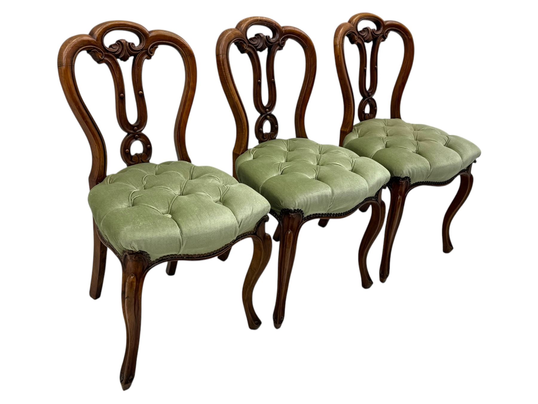 Set of six carved Victorian walnut balloon back dining chairs, button upholstered in green velvet fabric, back with foliate carved decoration supported on scroll form legs 