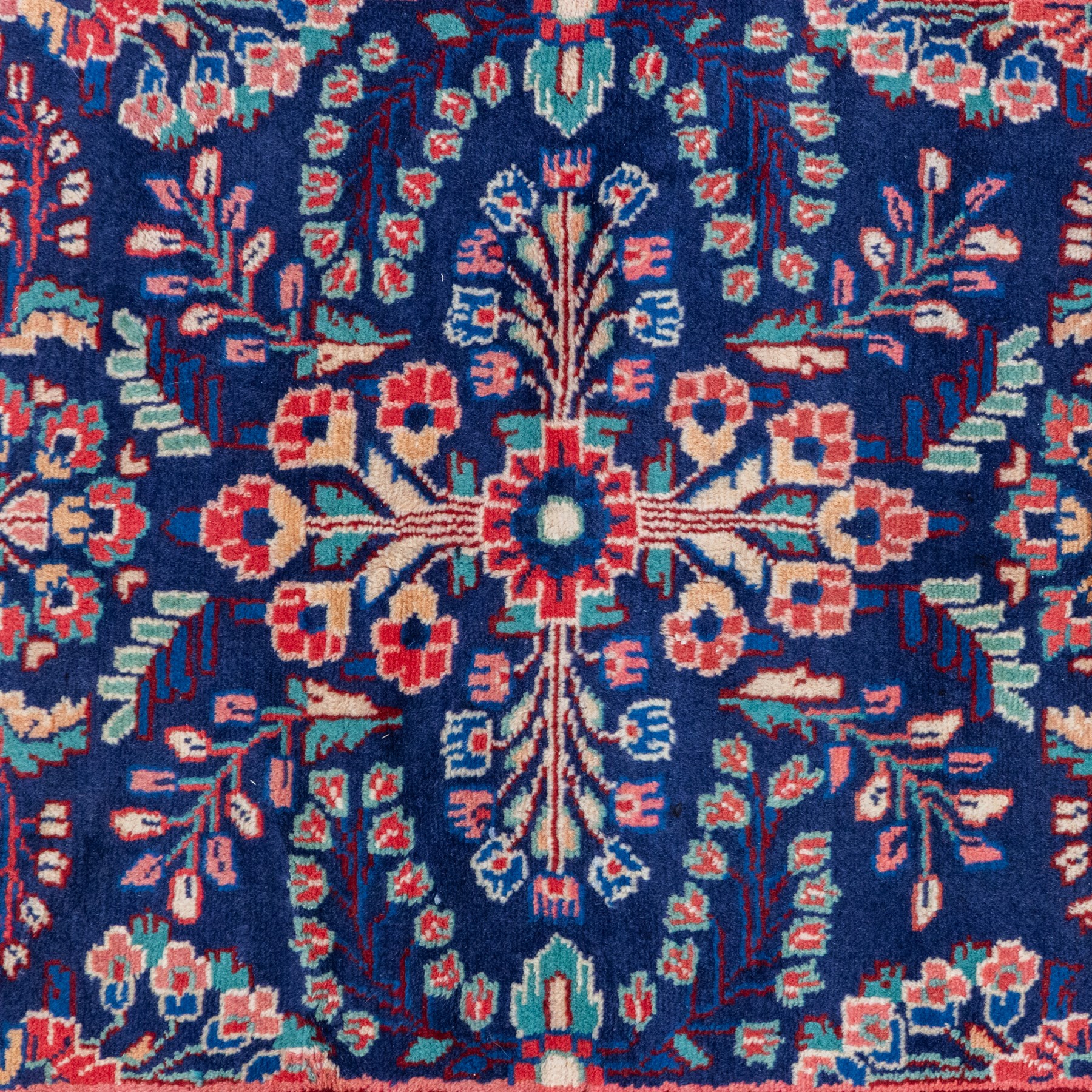 North West Persian runner, the indigo field decorated with repeating symmetrical floral sprays, rosettes and curling foliage in coral, ivory and pale blue tones, enclosed by a red ground trailing flowerhead border and narrow patterned guard bands 