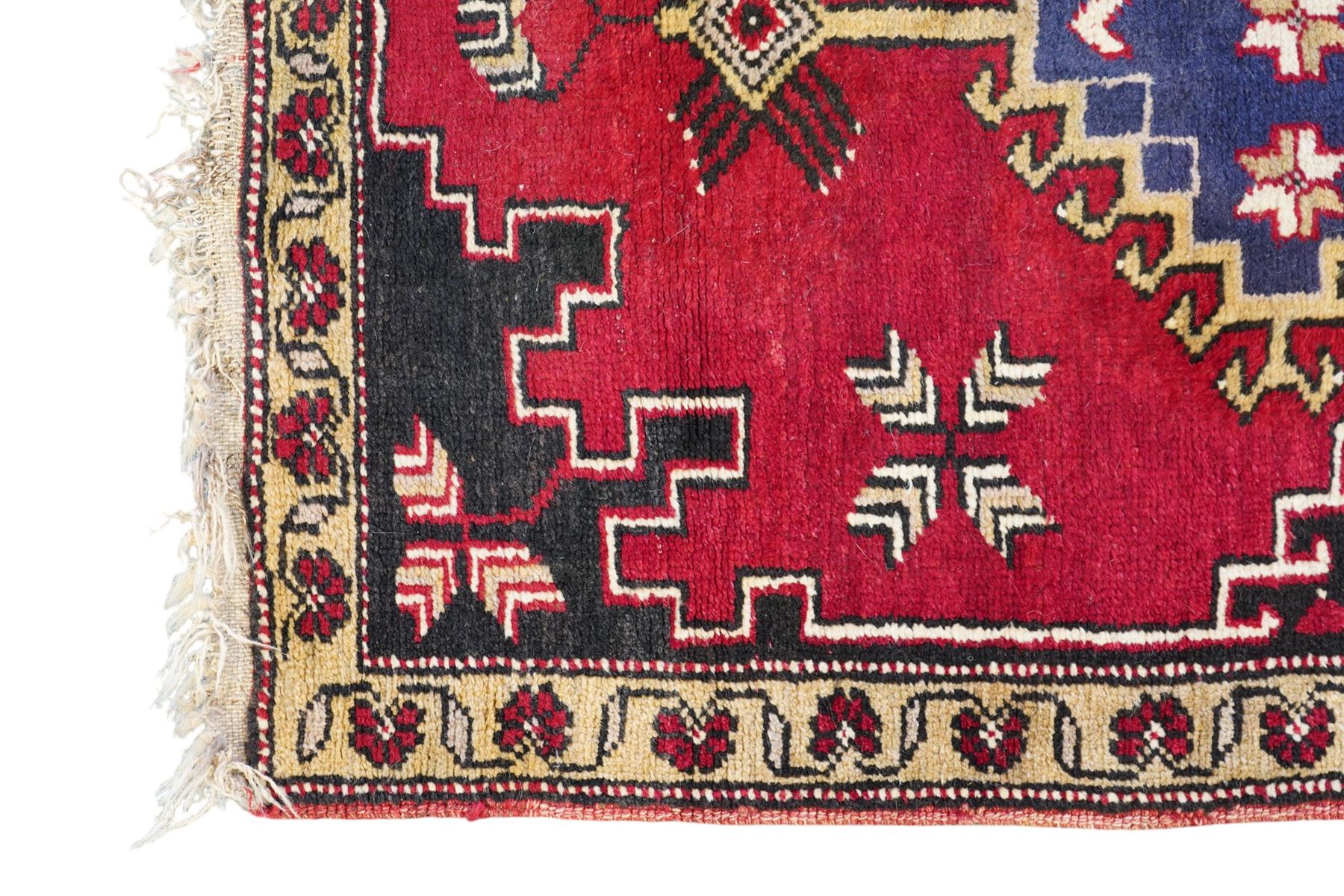 Turkish crimson ground rug, the field decorated with four hooked lozenges, trailing border with stylised flower heads 