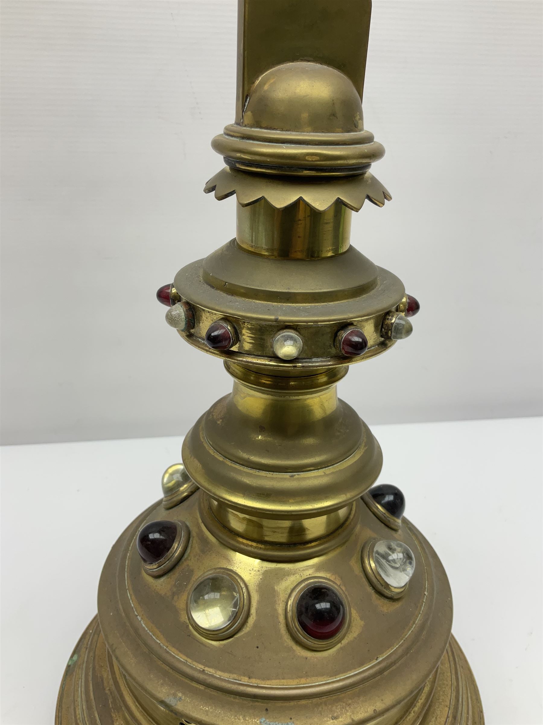 Brass alter cross, decorated with glass cabochons, upon a acicular stepped base and three claw feet, H73cm 