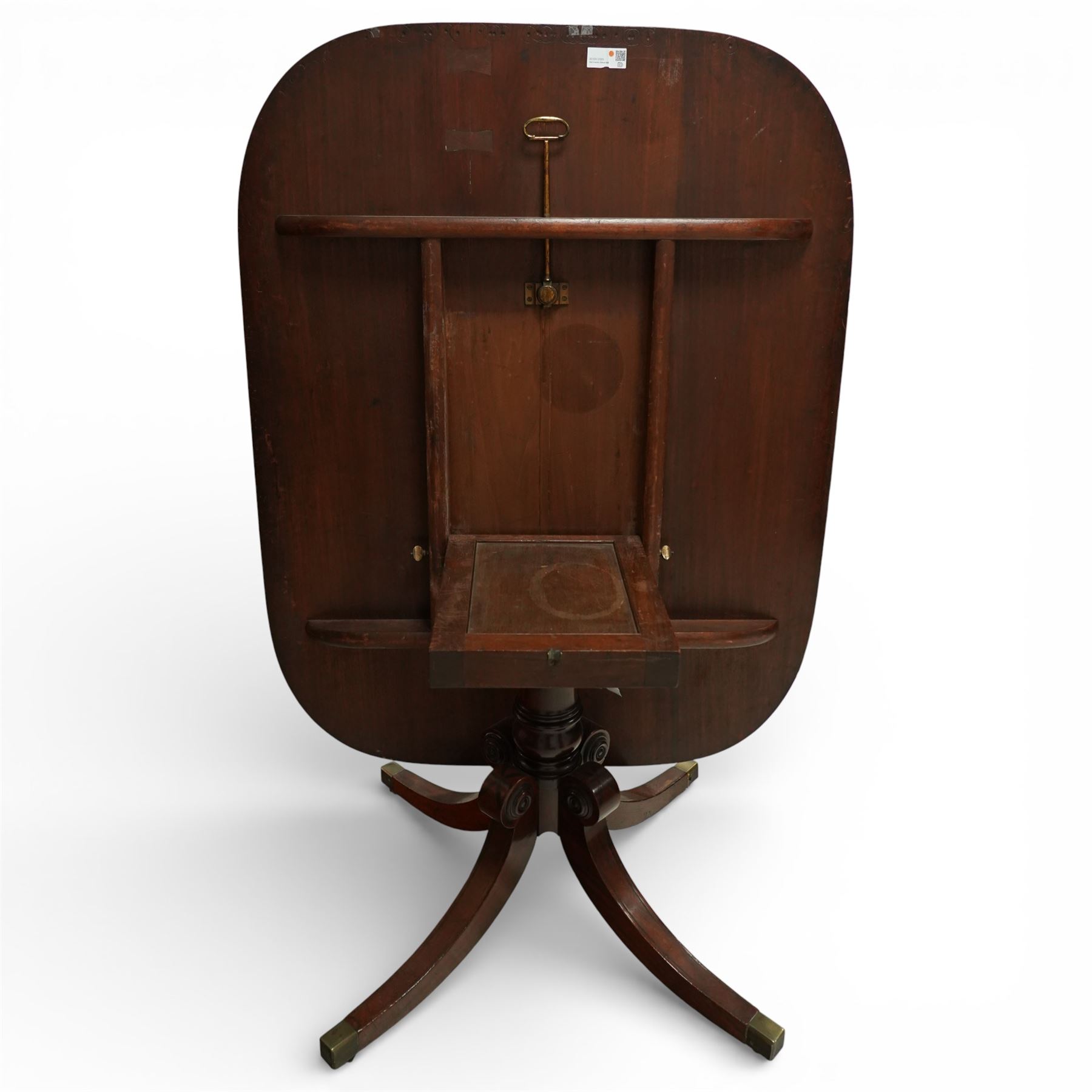 Regency figured mahogany breakfast table, figured rectangular tilt-top with rounded corners and rosewood banding, on turned column with four out-splayed supports with brass cups and castors 