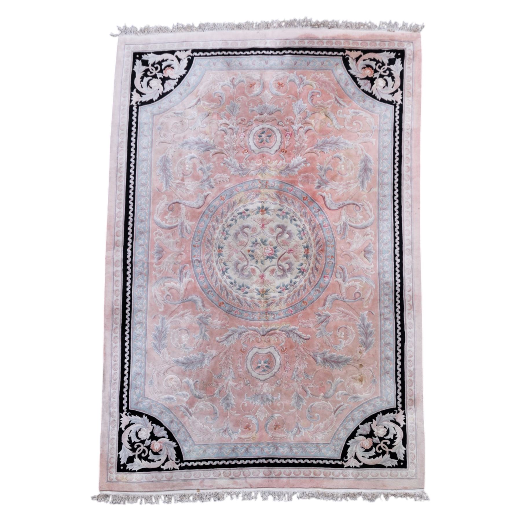 Large late 20th century Aubusson style wool carpet, peach and pastel toned field with central floral medallion enclosing scrolling acanthus and and foliate sprays, surrounding field decorated with further stylized foliage and and floral ornament, within shaped reserves and indigo corner spandrels, enclosed by narrow guard border, cotton fringe ends