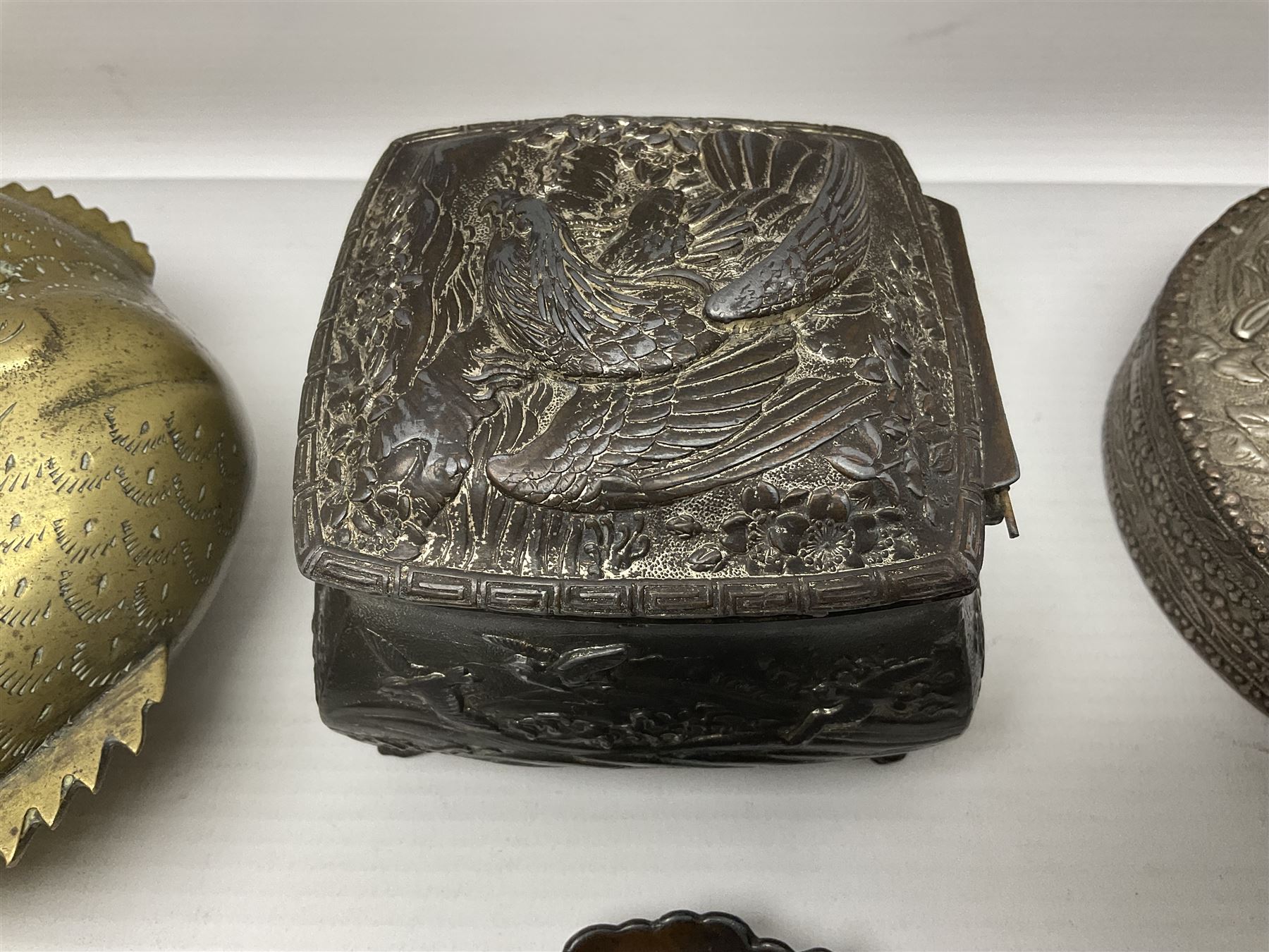 Brass sunfish ashtray, Chinese silver plated trinket box with mirror, bronzed matchbox cover and a collection of other Oriental bronzed embossed metal trays