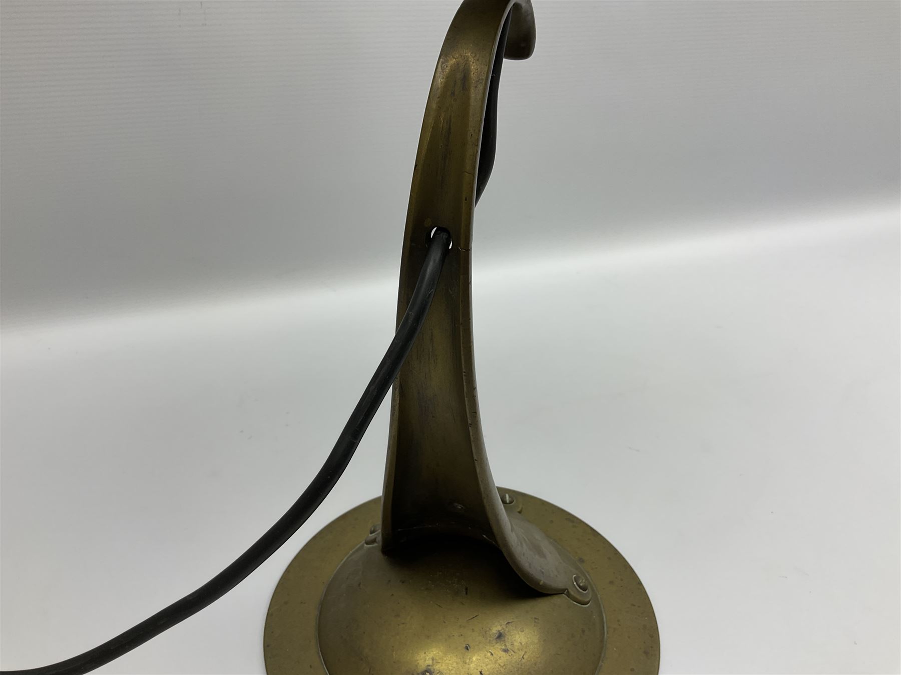 Arts & Crafts Jesson, Birkett & Co, brass table lamp or wall light, designed by Thomas Birkett, the tapering stem with adjustable ball pivot supporting a conical shade with tapering final with ball terminal, upon a circular domed base pierced for wall mounting, shade positioned upright overall H57cm

Often misattributed to Arthur Stansfield Dixon for Birmingham Guild of Handicraft, this particular lamp was designed by Thomas Birkett.
In the late 1890's Birkett worked as a metalwork at the Birmingham Guild, before later joining the Faulkner Bronze Company which went on to become Jesson, Birkett & Co in 1904. The lamp features in lighting catalogues from the firm under the model no E490.

