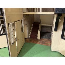 Large Tri-ang No.93 doll`s house in the 'Stockbroker's Range' c1935; two-storey double-fronted Tudor design, half timbered gables, two-storey bay windows, cream and mock shrubbery to front, opening metal framed windows with green shutters, red simulated tiled roof with chimney, integral garage with opening doors, front elevation has four hinged doors opening to reveal two bedrooms with fire places, living room, bathroom and kitchen with built in dresser and sink, entrance hall and staircase, side entrance with porch and seat and sun dial over on chimney stack; some wiring for electrical lighting; metal Tri-ang Toys disc verso; comprehensively furnished H66cm L117cm D43cm