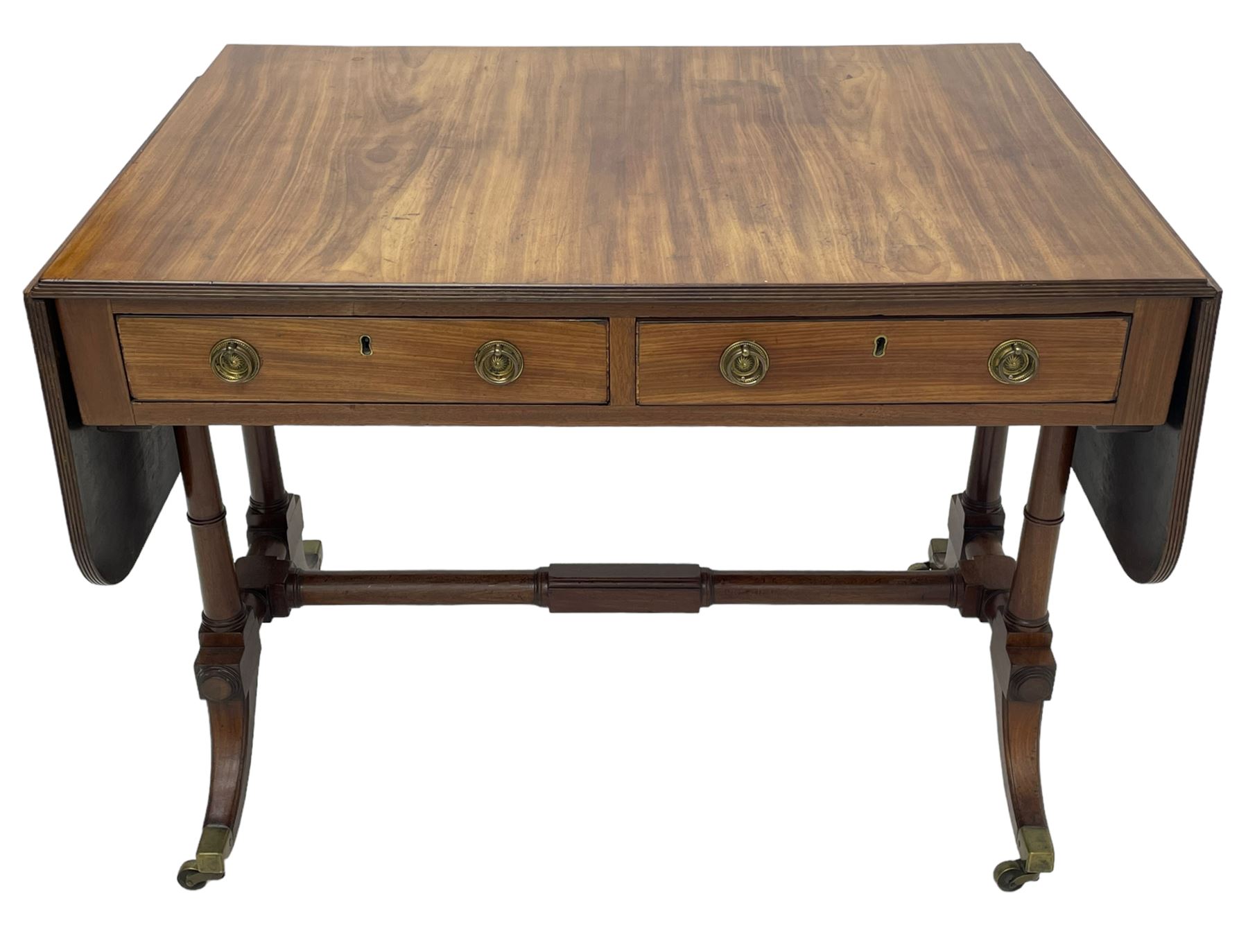 George III mahogany sofa table, rectangular drop-leaf top with reed moulded edge and rounded corners, fitted with two frieze drawers and two opposing false drawers, quadruple collar turned pillar supports on turned and block platforms, splayed and moulded supports with brass cups and castors 