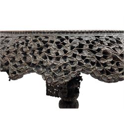 Late 19th century Anglo-Indian carved hardwood occasional table, circular tilt-top carved profusely with mythical animals and foliage decoration, pierced and carved with interlaced leafy branches, leaf carved pedestal supports on a raised platform with further carved and pierced foliage decoration, four carved feet in the form of mythical beasts with gaping jaws 