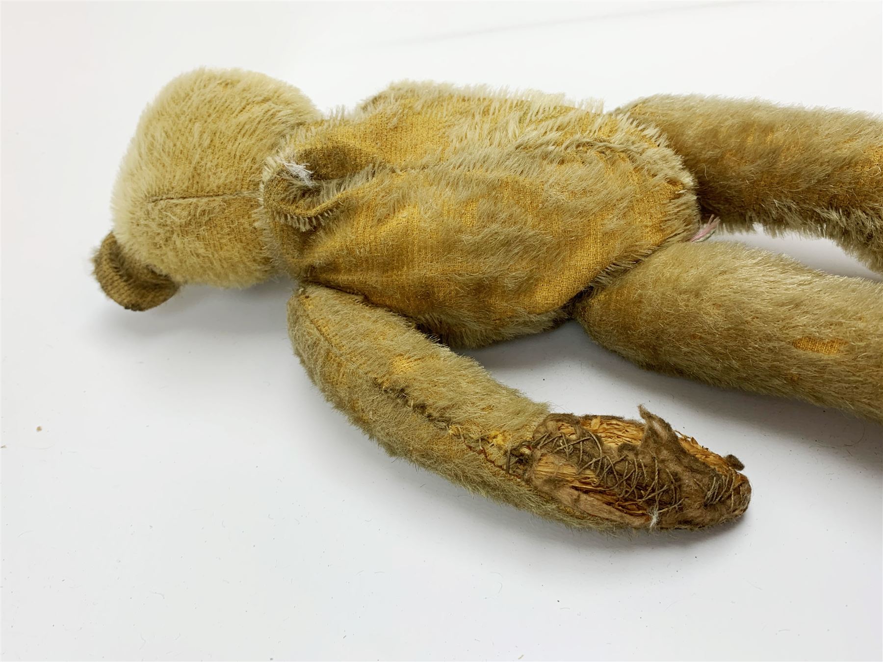 Early 20th century American mohair teddy bear c1920 with wood wool filled body humped back body with jointed limbs, black boot button eyes and horizontal stitched nose and mouth H12