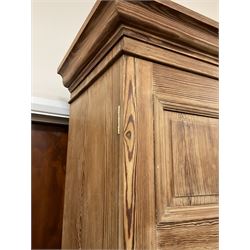 Victorian pitch pine double wardrobe, projecting moulded cornice over two panelled doors, the interior fitted with hanging rail and hooks, single drawer to base