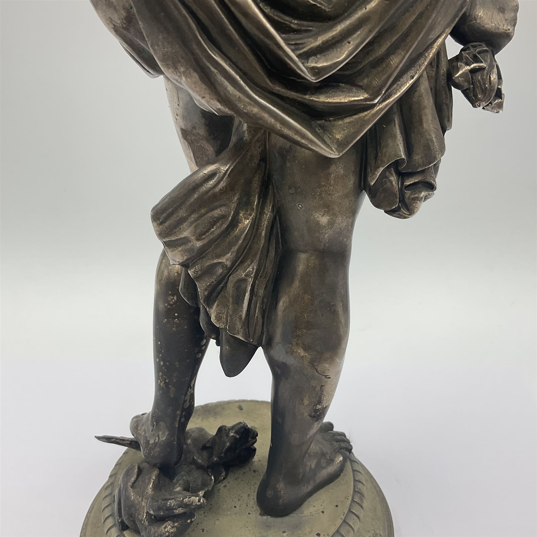 20th century silver plated figure, modelled as a classical male figure, possibly Prometheus, holding flames, one foot resting atop a small dragon, upon a circular spreading base, overall H37.5cm