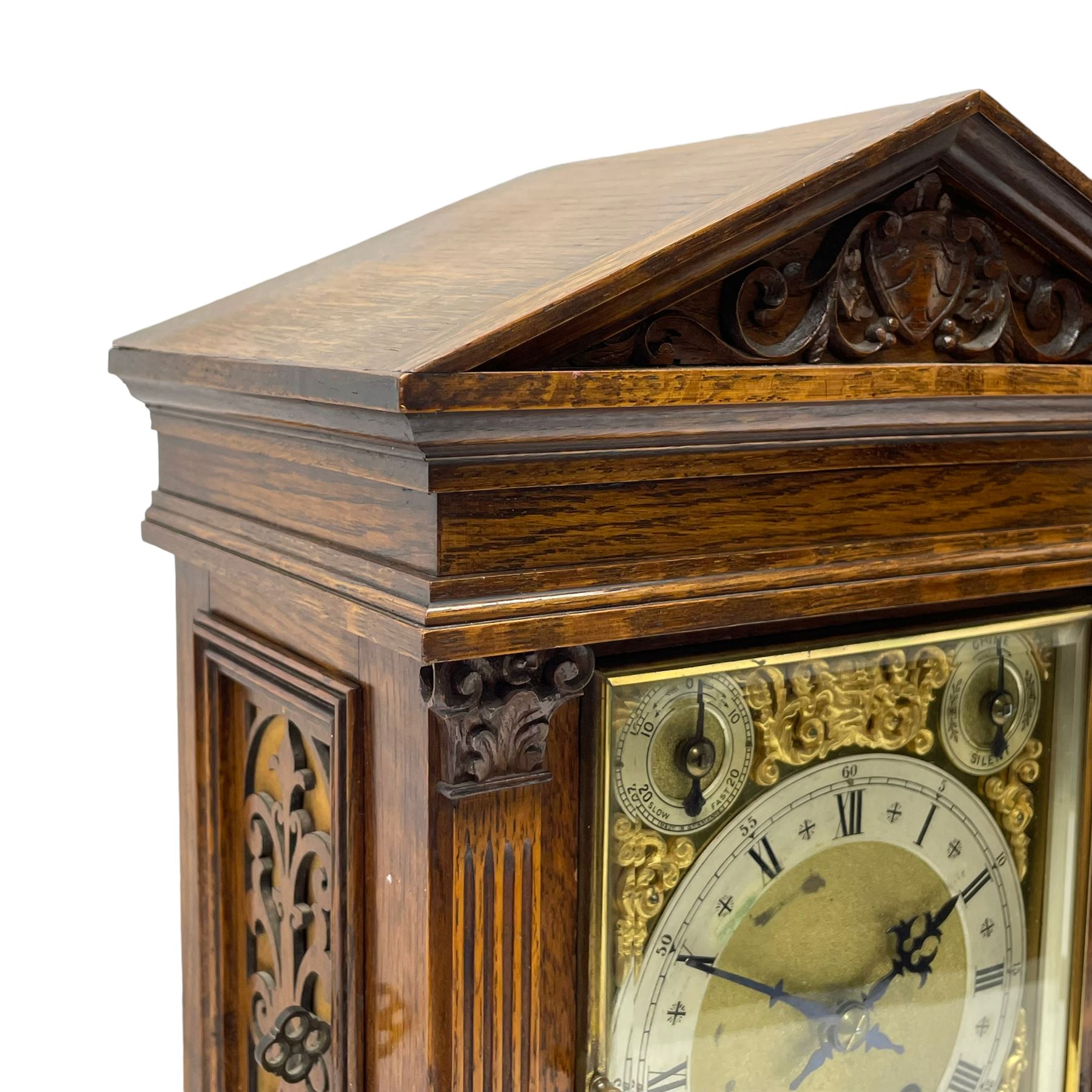 Winterhalder & Hofmeier- German 8-day oak cased mantle clock, in an architectural styled case with a gable pediment and recessed carving to the tympanum, square brass dial flanked by carved reeded pilasters and capitals, with open carved silk backed sound frets on a shaped plinth with padded feet, brass dial with cast spandrels and silvered chapter, Roman numerals, minute track and stylised gothic hands, conforming chime/silent and pendulum regulation dials, twin train going barrel movement with quarter-hour striking on two coiled gongs and the hours on one.
With pendulum.