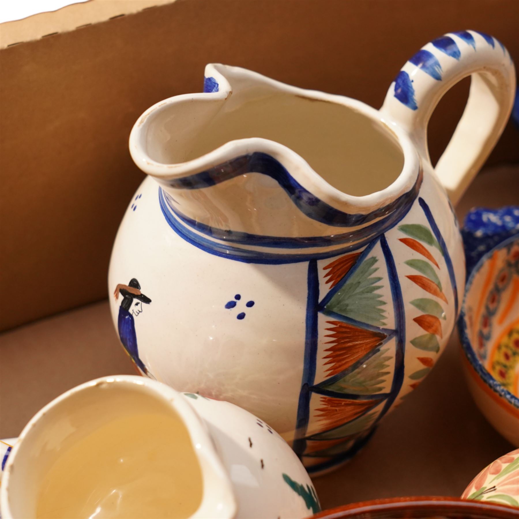 Collection of Quimper faience items including plates, cups, bowls and jug etc