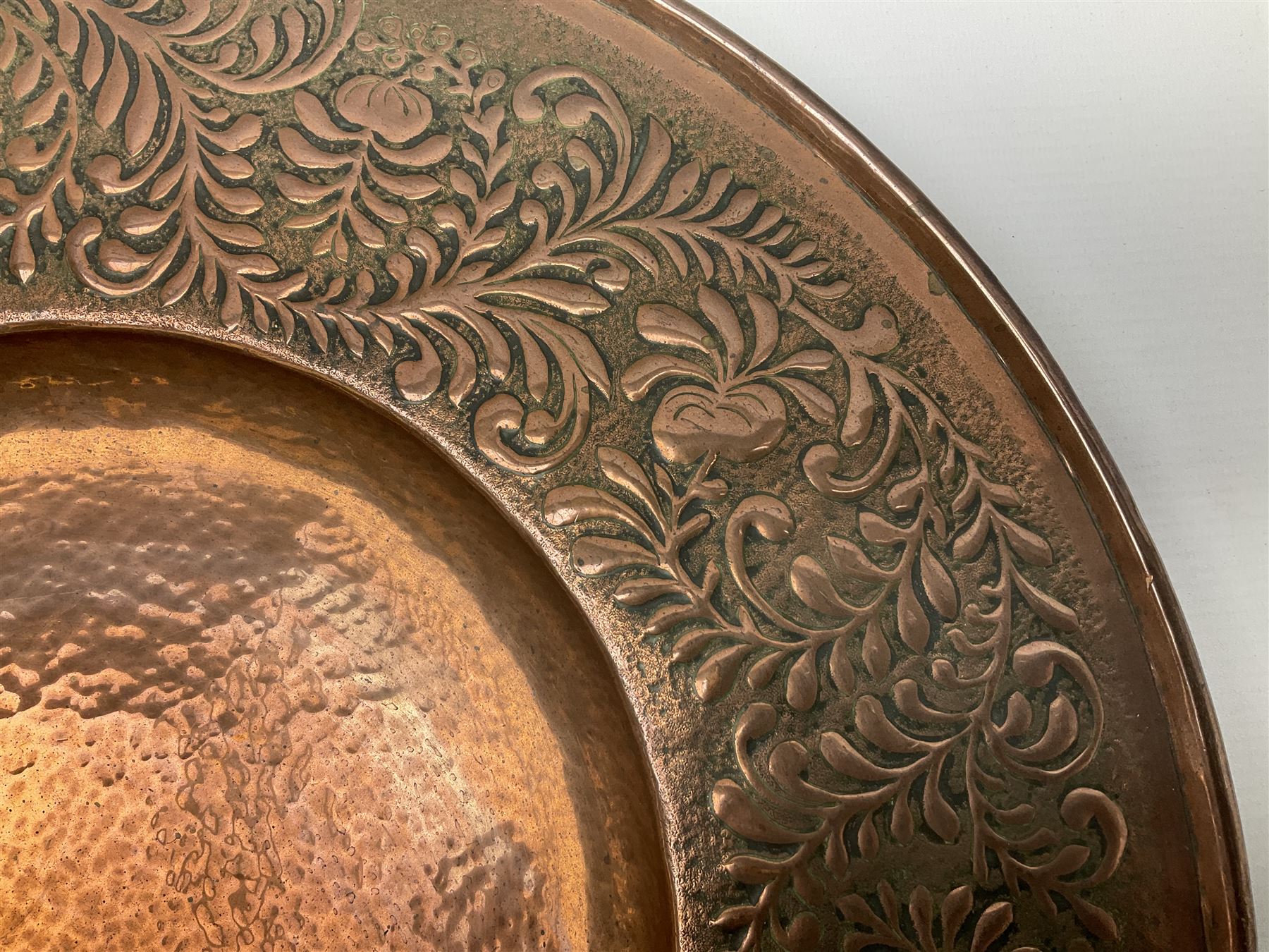Arts and Crafts Keswick School of Industrial Arts copper charger, decorated with planished centre and repousse scrolling foliate tendrils to rim, D44cm
