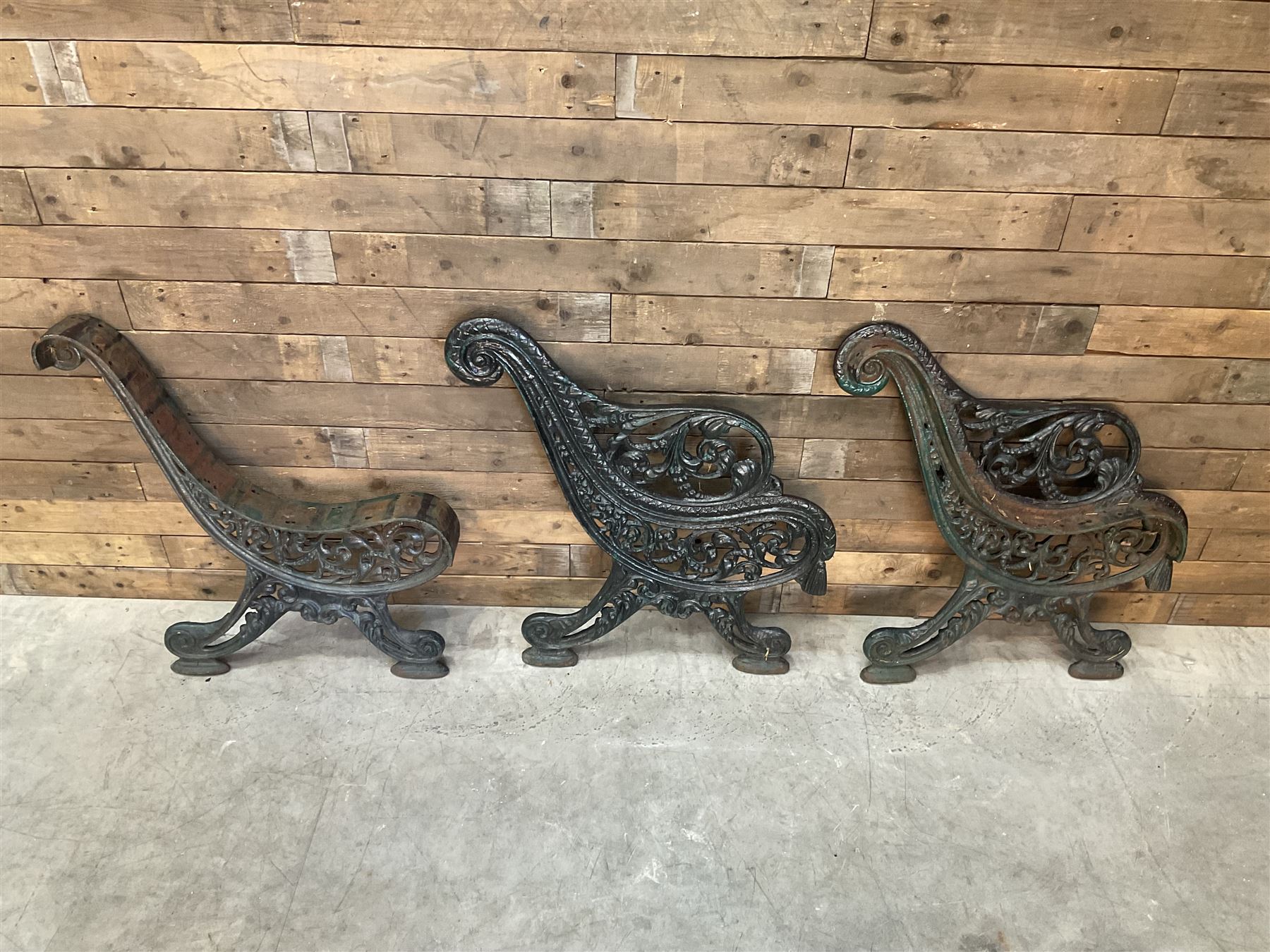 Early 20th century heavy cast iron three piece bench ends, decorated with scrolls and floral swags
