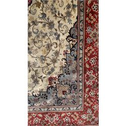 Central Persian Kashan rug, ivory and teal ground, overall geometric design, angular interlaced decorated field with stylised plant motifs, crimson ground, central medallion, the crimson main border band decorated with geometric motifs