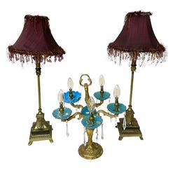 Brass table lamp, modelled as a candelabra with five branches, each with blue glass candle holders with crystal drops, H47cm, together with a pair of cast metal table lamps with acanthus leaf detail, upon a stepped square base, with red fabric feather and tassel shades, H78cm