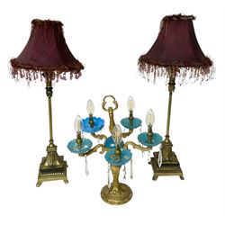  Brass table lamp, modelled as a candelabra with five branches, each with blue glass candle holders with crystal drops, H47cm, together with a pair of cast metal table lamps with acanthus leaf detail, upon a stepped square base, with red fabric feather and tassel shades, H78cm