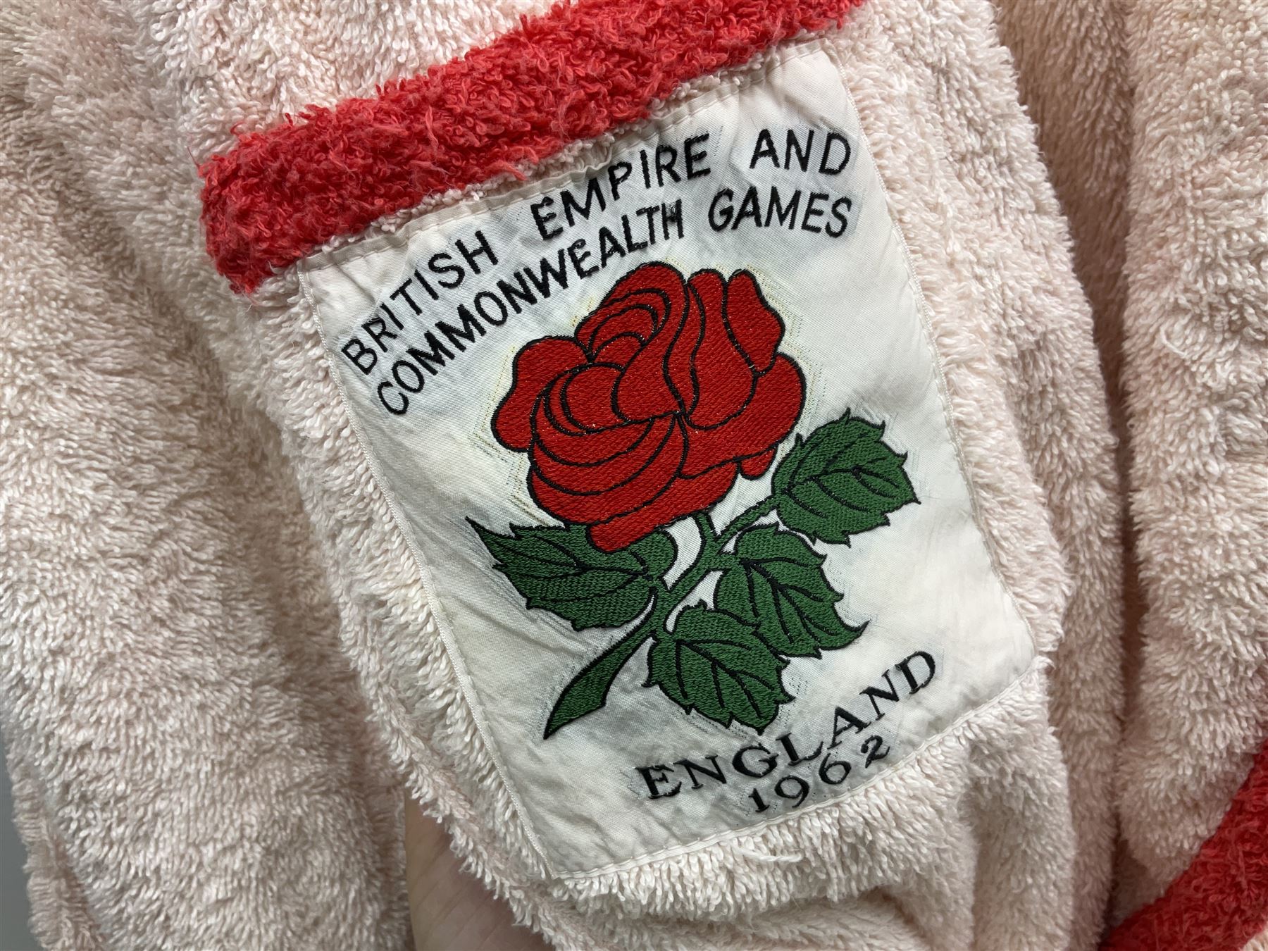 On the direct instructions of Anita Porter nee Lonsbrough Great British Olympic and Commonwealth Games gold medal winning swimmer - collection of early and international memorabilia comprising original Huddersfield Bath Club track suit top bearing eight stitched on cloth badges including British Empire & Commonwealth Games 1958 England Team, YSASA, North Eastern Counties ASA, ESSA Division 3,  English Schools Swimming Association winner etc
The swimming costume Anita wore at the 1958 Commonwealth Games in Cardiff, her first major championships, where she won two gold medals. The grey elastic on the sides, in those days, she would use to make it tighter and more streamlined.
Blue track suit from the 1960 Olympics which she wore on the podium receiving the gold medal.
1960 pool side towelling robe used at the Rome Olympics (interesting to note her name is spelt wrong on the embroidered label).
1962 Commonwealth Games pool side towelling robe used in Perth Australia when winning three Gold medals. 
It was also this year she became BBC Sports Personality of the year, the first female to do so.
Her 'lucky' pool side towel which she took with her to every event she competed in and which can be seen round her neck in many official celebratory photographs. Copies of some of these photographs are included for identification.
In addition there are two souvenir programmes of an evening event to honour Anita at The Theatre Royal Huddersfield and she has kindly signed the front cover on one of these.