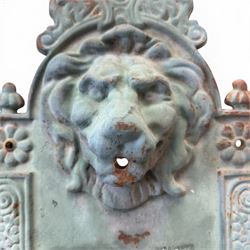 Antique cast iron wall fountain, cartouche cresting rail over a lion mask spout, with scroll and floral decoration over a scalloped basin, in rustic turquoise painted finish with rusted patina