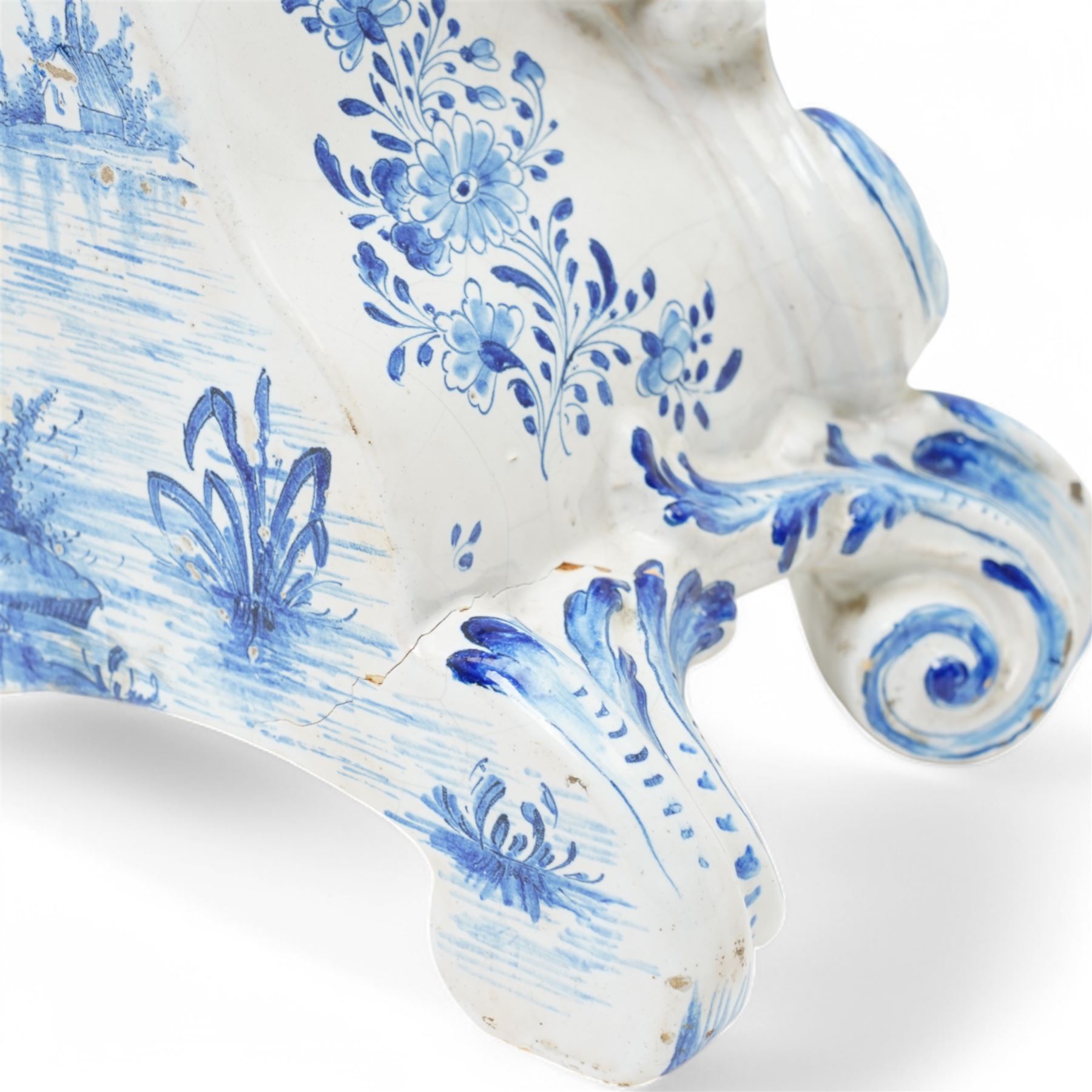 19th century delft blue and white Rococo style 8-day mantle clock, with a scrolling case and floral decoration, depiction of a courting couple in 18th century dress to the front and a contrasting scene of sailing ships on a lake to the rear, with a late 19th-century French twin train movement, enamel dial with Roman numerals, five minute Arabic's and gilt Louis XVI hands within a glazed cast bezel, with a rack striking movement sounding the hours and half-hours on a bell. No pendulum or key.  