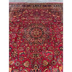 Persian Meshed carpet, red ground with central rosette medallion surrounded by interlacing foliage and stylised flower heads, repeating border with signature panel 