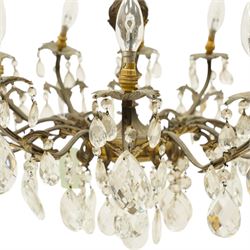 20th century Louis XV design gilt and patinated metal twelve-light chandelier, the foliate-cast baluster stem issuing scrolling acanthus branches with leaf-form drip pans, hung throughout with faceted glass pendants and lustre drops, suspended from chains beneath a foliate ceiling rose