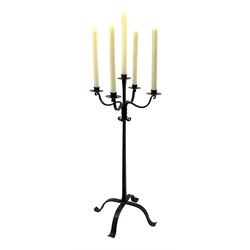 Wrought hand forged iron candle stand, four scrolled branches and central vertical branch with sconces, tapered column on four shaped and out splayed supports