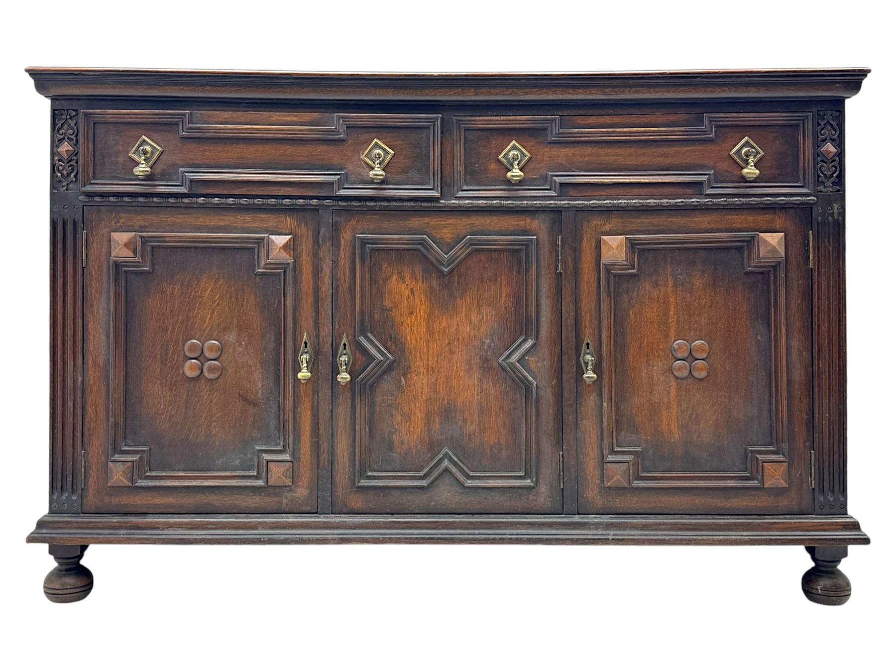 Jacobean-style oak dresser base with two frieze drawers above three cupboards with panelled and moulded decoration, fitted with drop handles, supported on bun feet, circa 1900