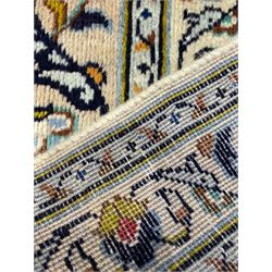 Persian Kashan Ivory ground carpet, the busy field decorated all over palmettes and trailing branches, scrolling border interspersed with stylised plant motifs, within guard stripes