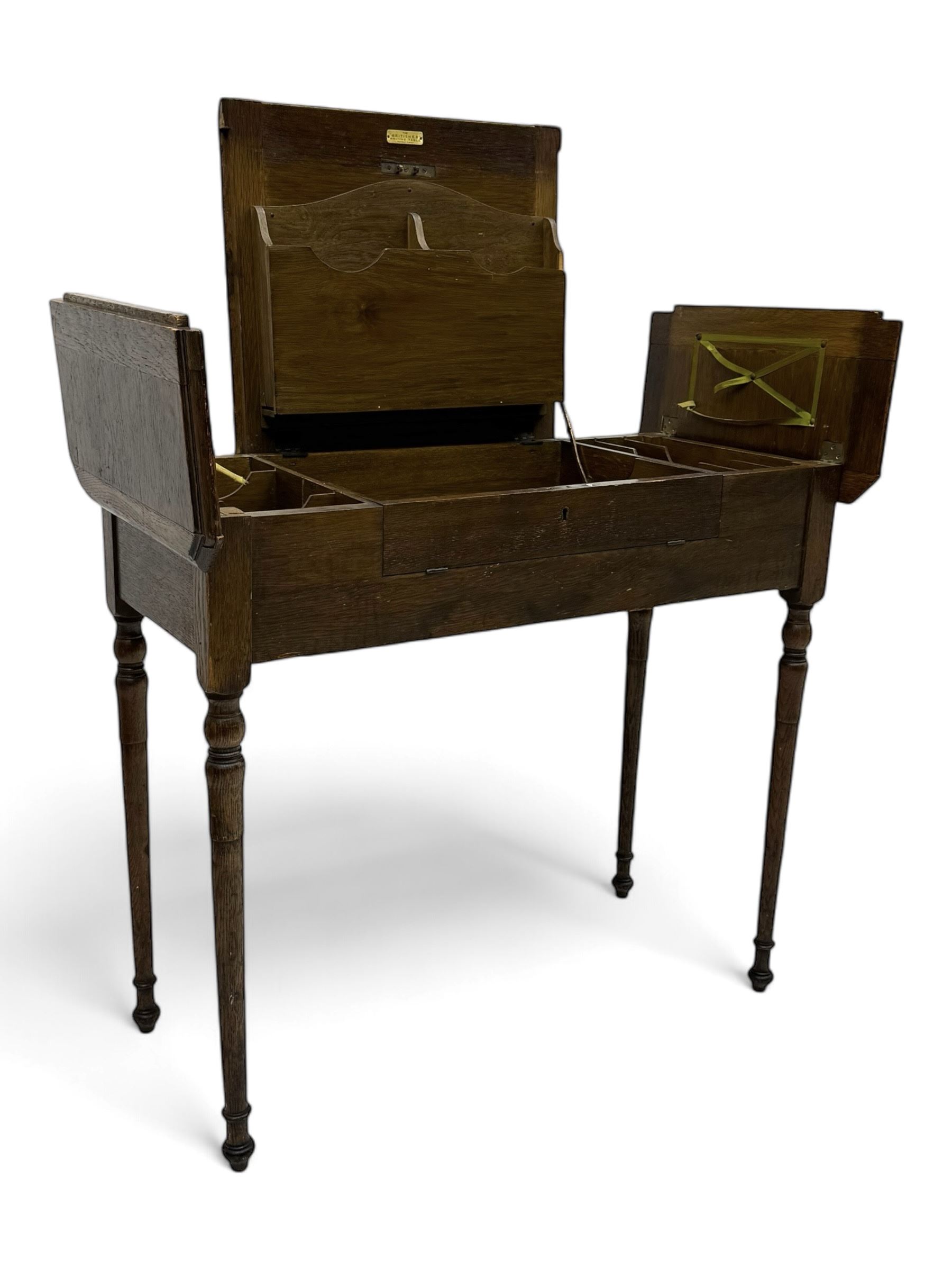 Edwardian oak metamorphic 'Britisher Writing Table', rectangular hinged top revealing correspondence compartments and hinged writing surface with underside storage, flanked by twin hinged compartments with dividers, on turned supports