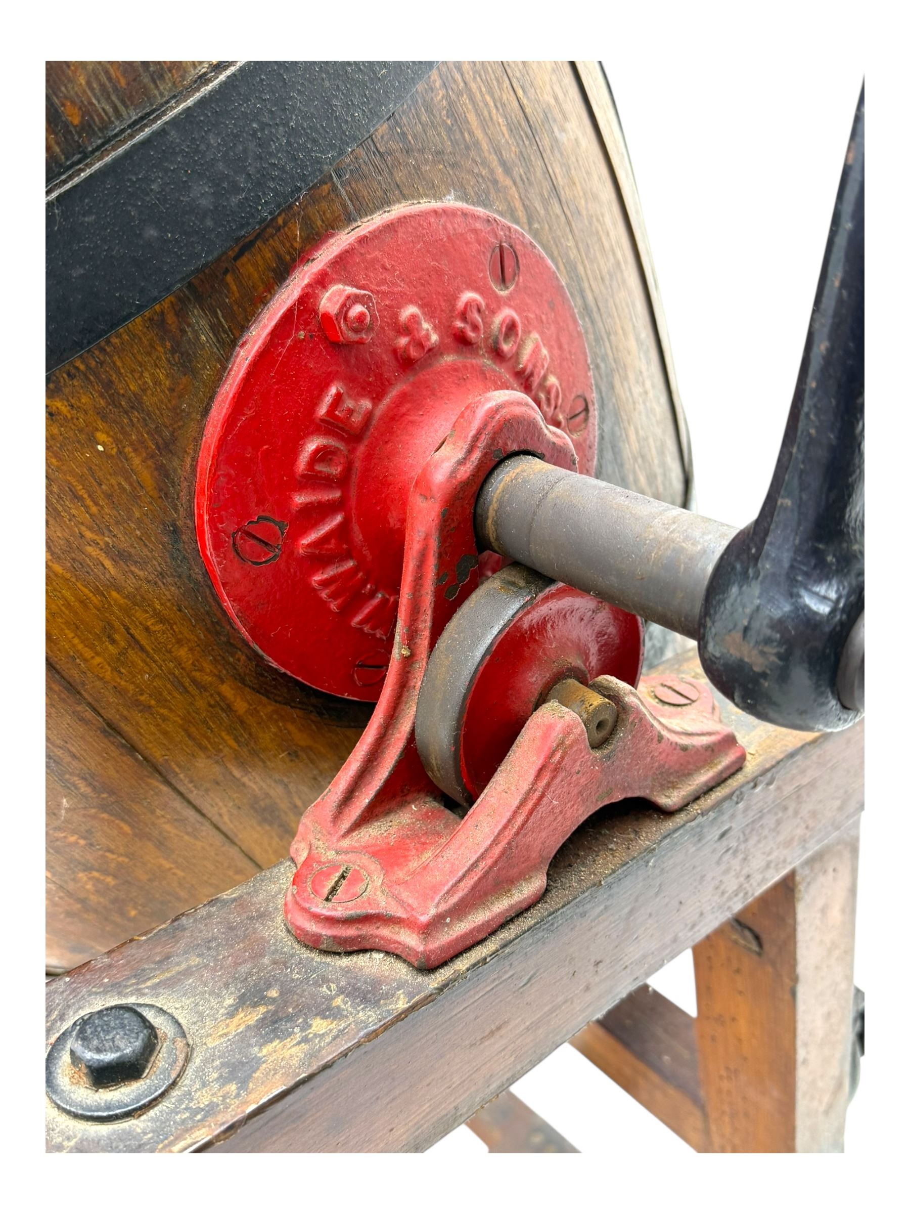 19th century oak and cast iron rotary butter churn, with coopered barrel body, domed lid with filler opening and cast iron securing arms, on tilting iron-mounted frame with crank handle and support rails