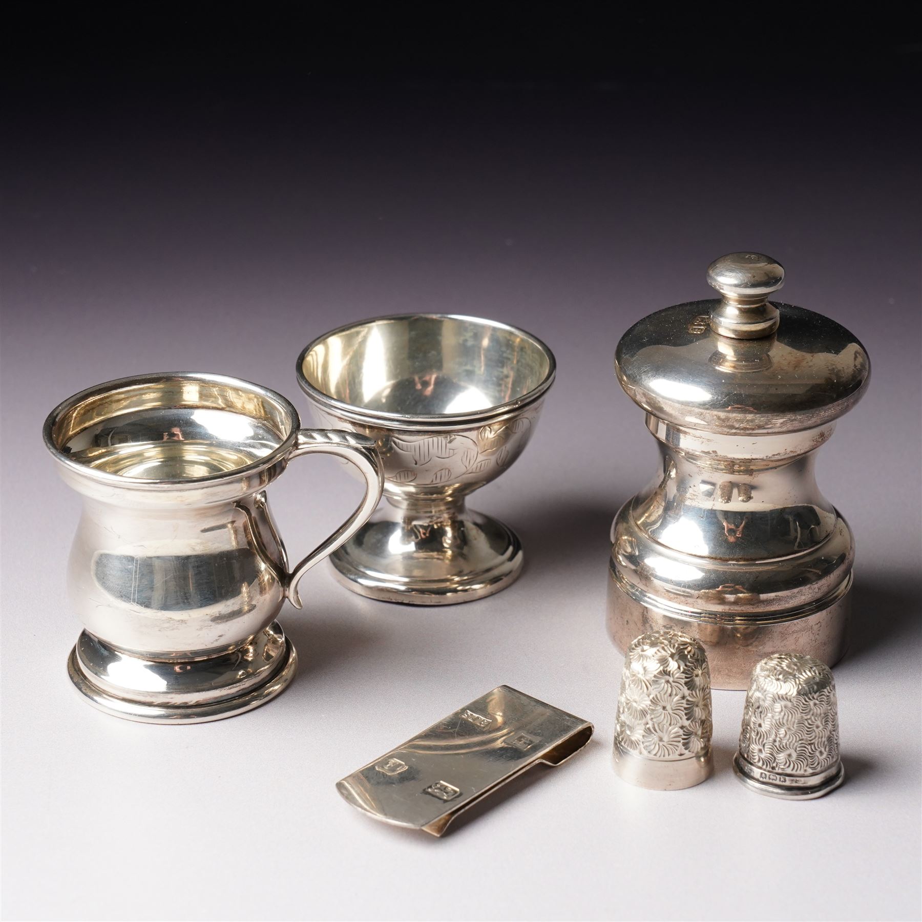 Small silver pepper mill H7cm London 1987,  small silver baluster measure, silver egg cup, two thimbles and a silver note clip
