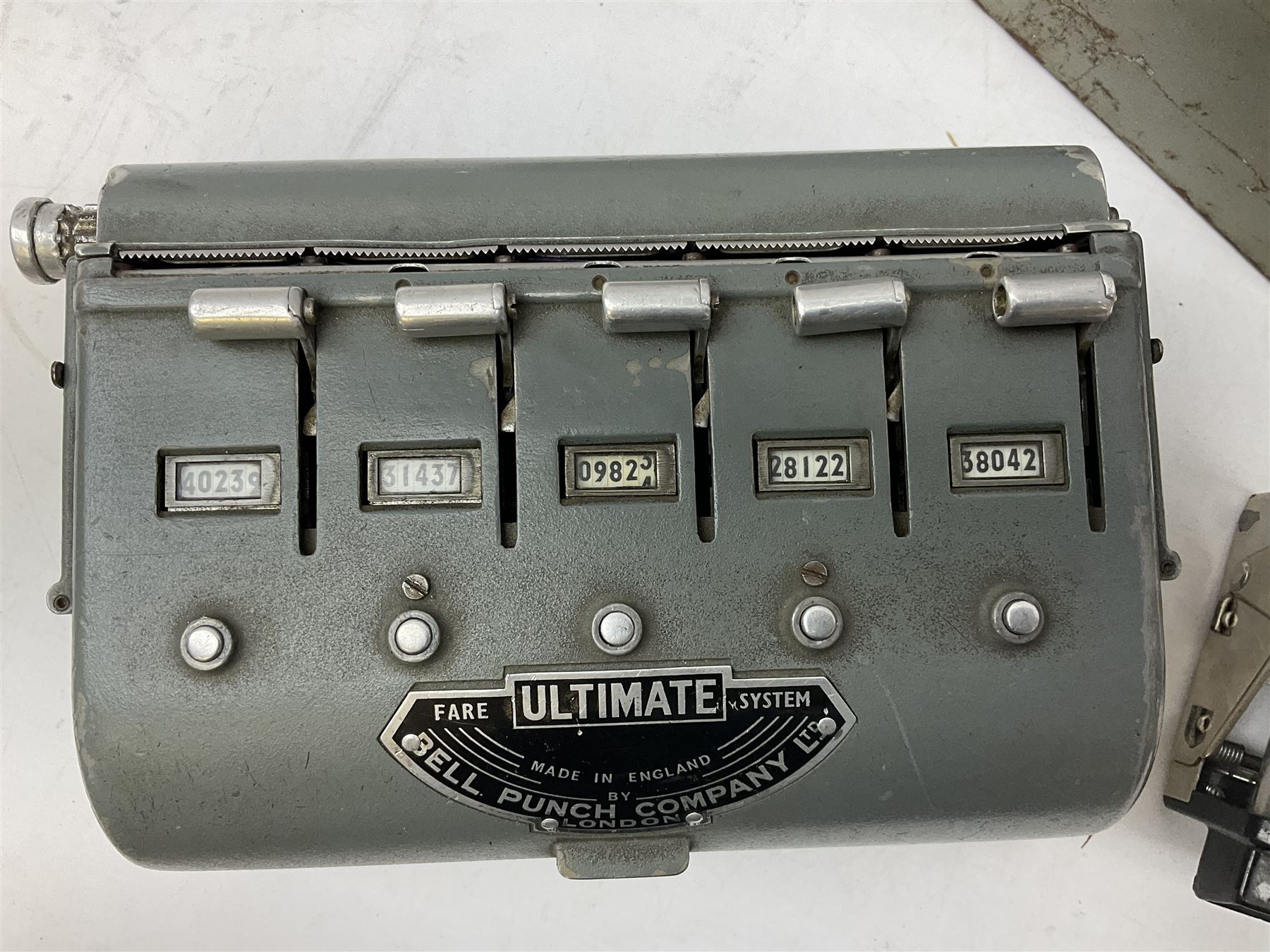 Bell Punch Company of London 'The Ultimate' five lever fare collection machine, together with an Almex ticket machine with shoulder strap, two brass Halifax transport cap badges, other chrome tramway cap badges, etc