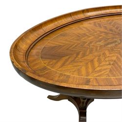 Early 20th century walnut coffee table, oval dished top with sunburst matched veneer, raised on twin cluster columns united by turned stretcher base on splayed supports